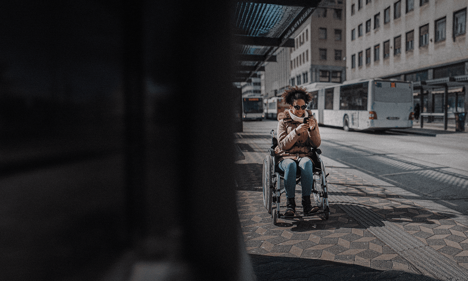 A woman in a wheelchair waiting at a bus stop